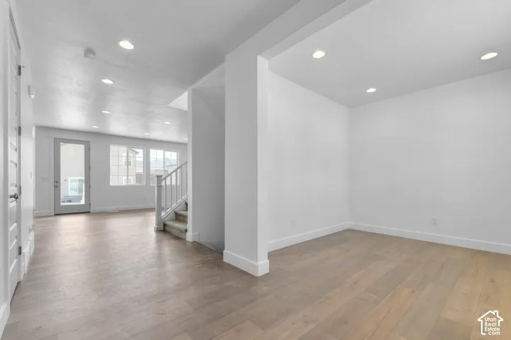 Open interior space featuring wood-finish flooring, recessed lighting, white walls, and a staircase with a white railing
