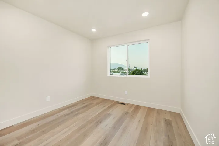 Neutral-toned interior featuring wood-finish flooring, recessed lighting, and a window with mountain scenery