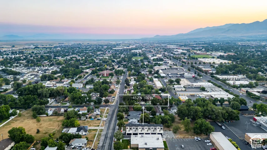 Aerial perspective of a multi-unit residential structure featuring a flat roofline, neutral exterior cladding, and mountain range backdrop