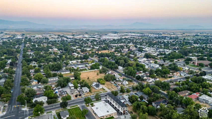 Aerial perspective of a multi-level residential structure featuring a flat roof and surrounding neighborhood landscaping against a mountain backdrop