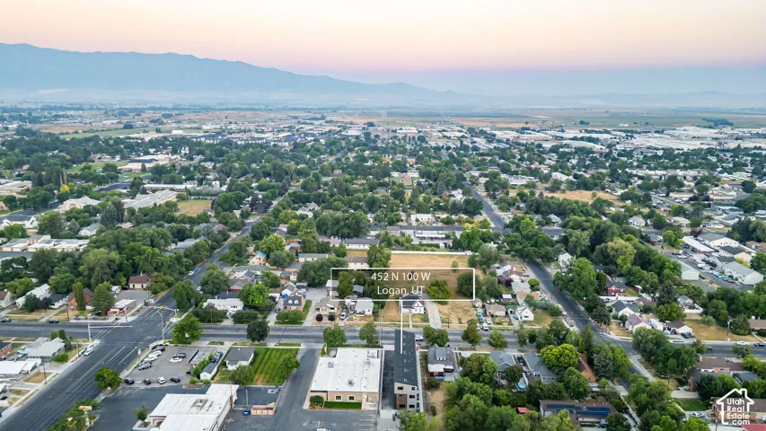 Aerial perspective of residential parcel featuring mature trees, flat topography, and backdrop of mountain ranges