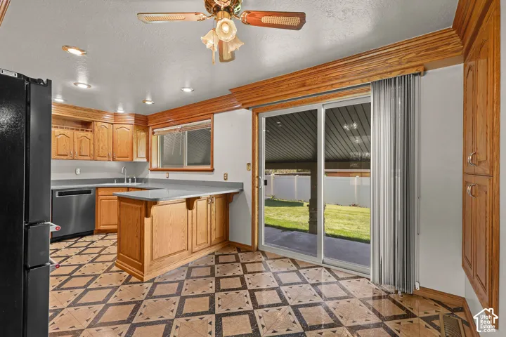 Kitchen featuring natural wood cabinetry, solid surface countertops, patterned tile flooring, recessed lighting, and a sliding glass door
