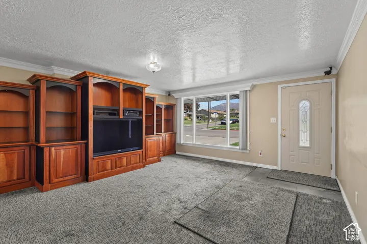 Built-in wood cabinetry, expansive picture window, tile entryway, textured ceiling, and crown molding
