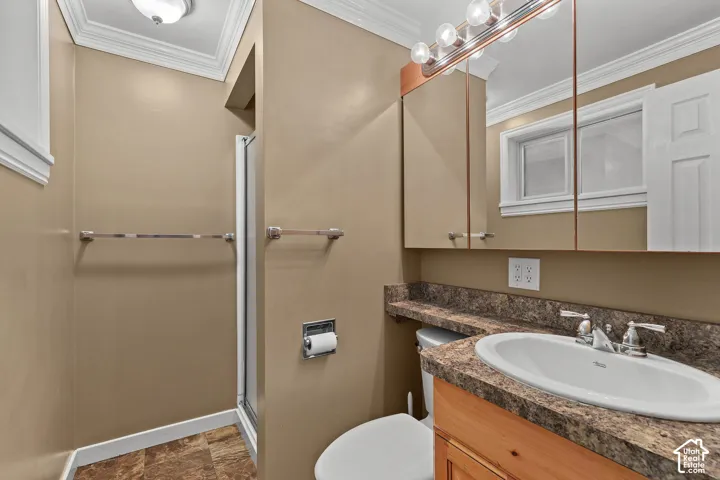 Bathroom featuring a vanity with a stone-finish countertop, integrated oval sink, wood-finish cabinetry, and a large mirrored medicine cabinet with multi-bulb lighting