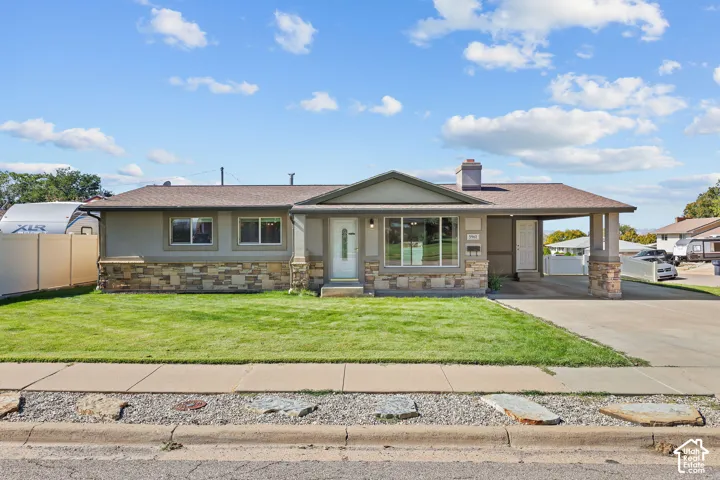 Single-level exterior featuring a stone-veneer facade, neutral-toned siding, a covered carport with stone-pillar supports, and a shingled roofline