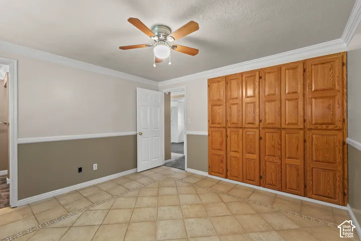 Tile flooring featuring decorative accent inlays, floor-to-ceiling wooden cabinetry, and a central ceiling fan