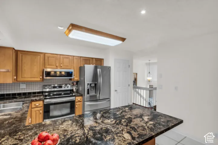 Kitchen featuring wooden cabinetry, granite countertops, stainless steel appliances, and a flush-mount overhead light fixture