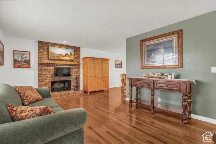 Brick fireplace with a mantel, accent wall, and wood-finish flooring