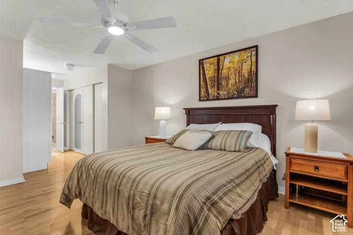 Light-toned wood-finish flooring, white-finish ceiling fan with integrated lighting, and closet doors featuring arched panel detailing