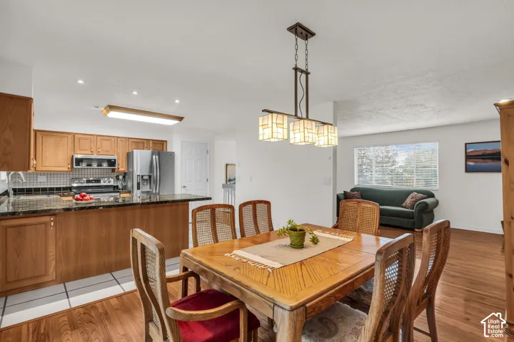 Kitchen featuring wood cabinetry, granite countertops, stainless steel appliances, tile flooring, and a multi-light pendant fixture