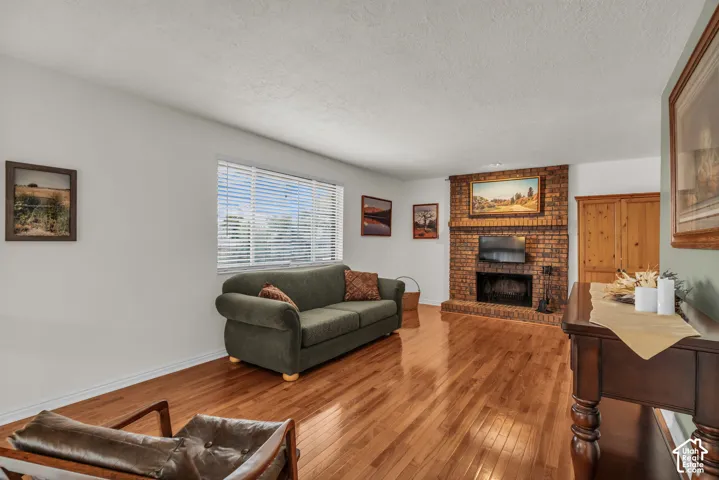 Living space featuring wood-finish flooring, a floor-to-ceiling brick fireplace, and a large horizontal window