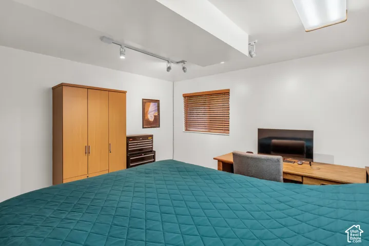 Adjustable track lighting, built-in light-tone wood cabinetry, and window blinds