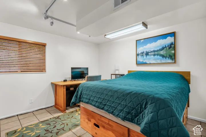 Room featuring tile flooring, adjustable track lighting, flush-mount fluorescent overhead lighting, and horizontal wood-finish blinds