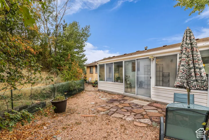 Four Seasons sunroom with white horizontal siding and a flagstone patio area