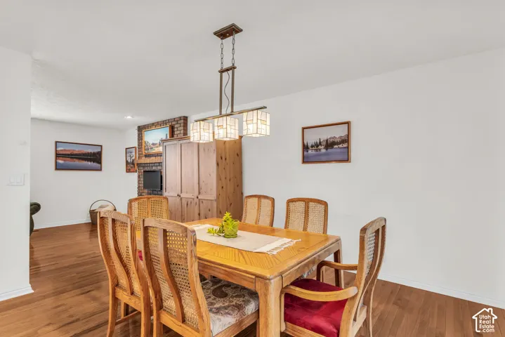 Oak wood flooring, brick fireplace with a wood mantel, and three-light rectangular pendant fixture