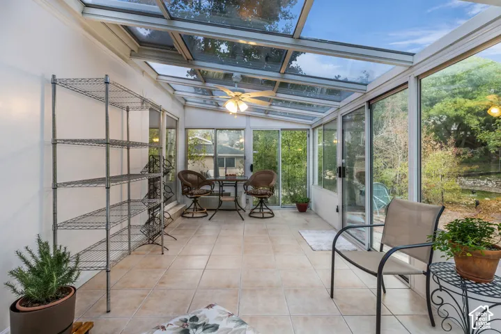 Four Seasons Sunroom featuring a glass panel roof, tile flooring, sliding glass exterior doors, and a ceiling-mounted light fixture with water, heat and AC