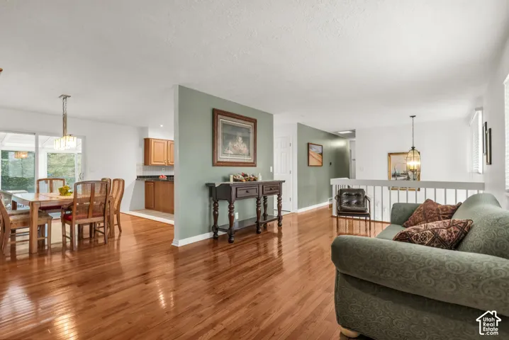Open-concept area featuring wood-finish flooring, two decorative pendant light fixtures, and a white wooden stair railing