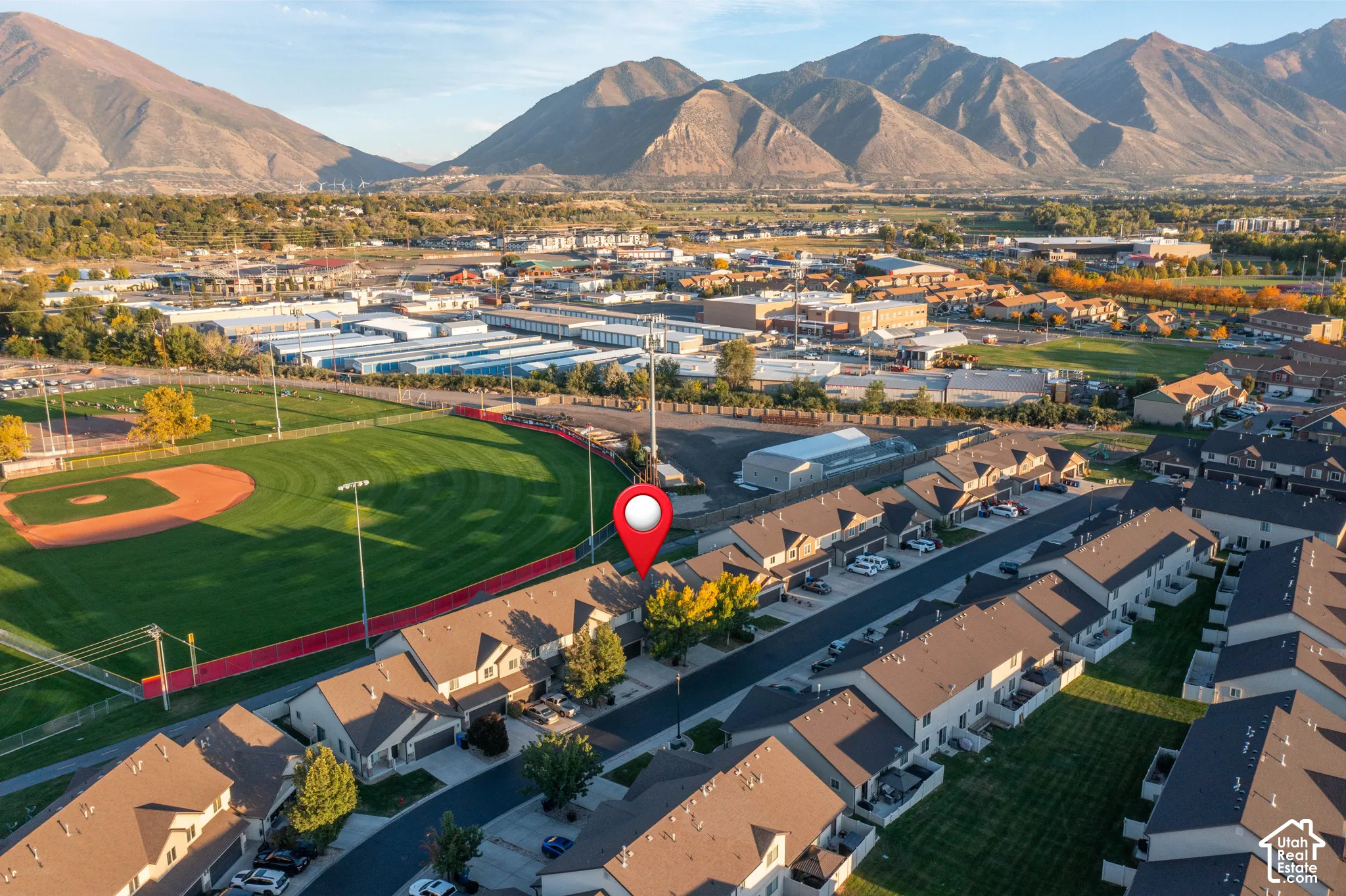 Aerial perspective featuring multi-story residential structures with pitched roofing, concrete driveways, and expansive mountain terrain backdrop