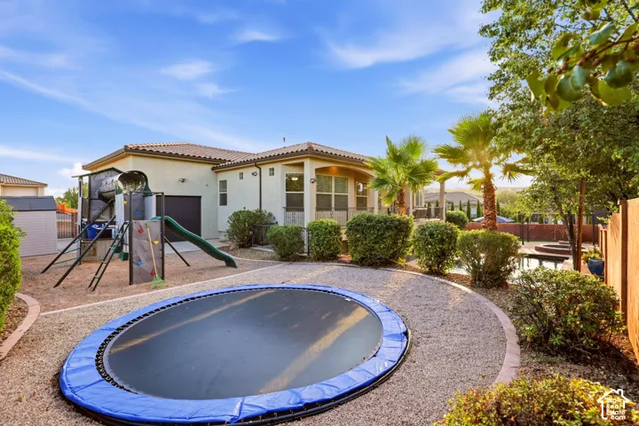 Backyard featuring a covered patio, swimming pool with spa, gravel landscaping, and established palms