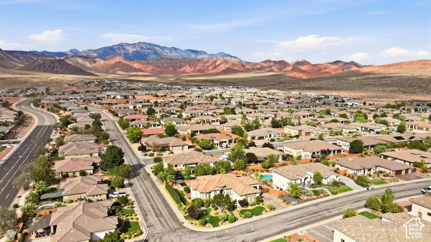 Aerial perspective of a residential neighborhood featuring paved streets, mature landscaping, and a prominent backdrop of desert mountain ranges