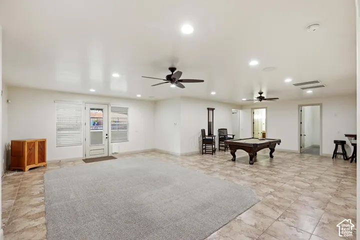 Spacious room featuring tile flooring, recessed lighting, dual ceiling fans, and a glass-paneled exterior door