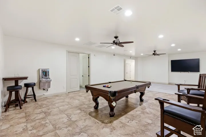 Large open-concept interior featuring stone-tile flooring, recessed ceiling lighting, dual ceiling fans, and an integrated wall-mounted water fountain