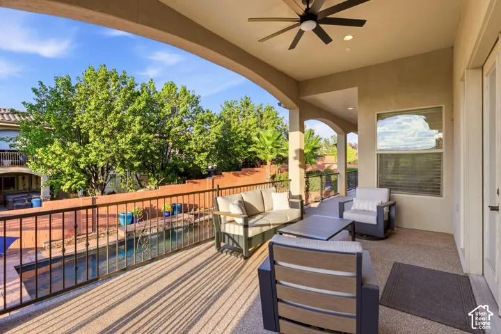 Covered patio featuring aggregate concrete flooring, an integrated ceiling fan, recessed lighting, and metal perimeter railing overlooking a concrete-bordered pool