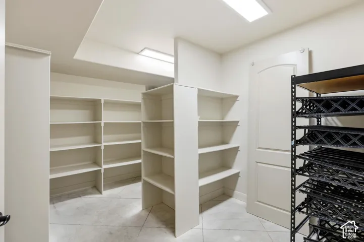 Walk-in storage space featuring custom built-in shelving, tile flooring, and recessed ceiling lighting