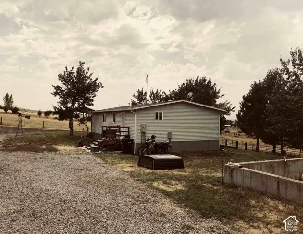 2nd Home. Single-story residence with horizontal siding, gravel driveway, and surrounding natural landscape
