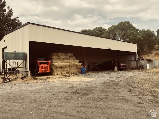 Metal-sided barn featuring an open-sided structure, covered storage area, and a gravel foreground