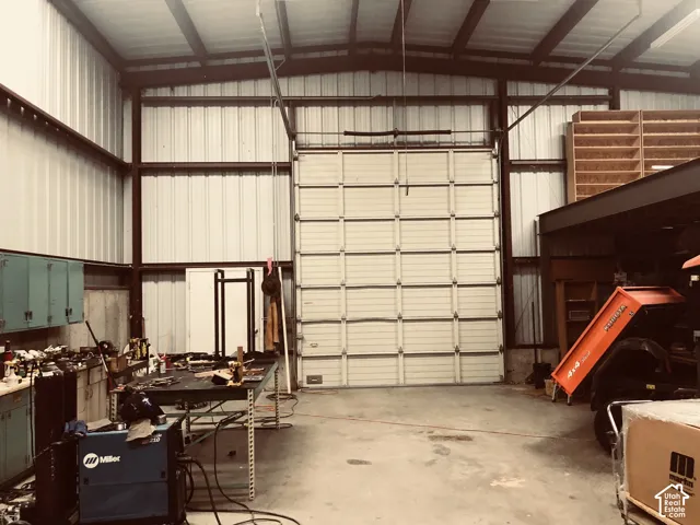 Industrial-style metal building featuring a large overhead door, exposed structural beams, and a concrete floor