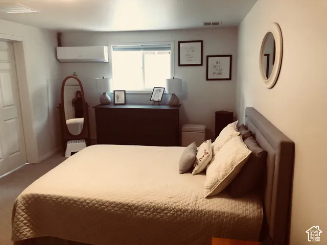 2nd Home. Room featuring neutral wall tones, carpeted flooring, a horizontal sliding window, and a wall-mounted ductless heating and cooling unit