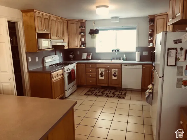 Kitchen featuring wood-finish cabinetry, light-toned tile flooring, and a built-in kitchen island