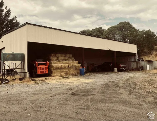 Agricultural structure with a corrugated metal roof and siding, featuring multiple open bays, and a gravel foreground