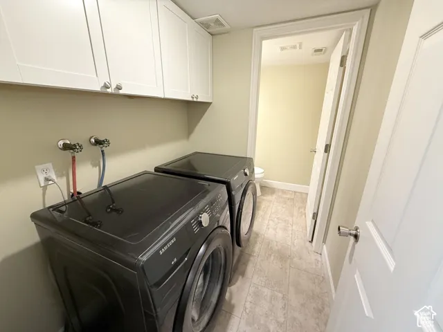 Laundry room featuring white wall-mounted cabinetry, tile flooring, and a multi-panel door