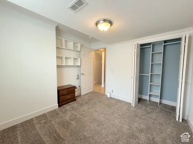 Room featuring neutral wall-to-wall carpeting, built-in wall shelving, a bi-fold closet with integrated shelving, and a multi-panel interior door