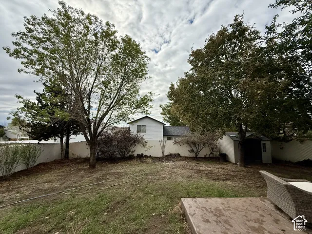 Backyard featuring a concrete patio, perimeter vinyl fencing, and mature trees