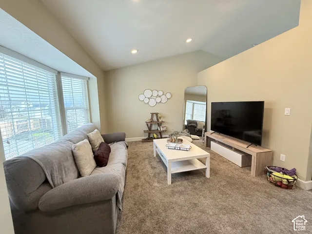 Vaulted ceilings featuring recessed lighting, carpeted flooring, and a multi-pane bay window with horizontal blinds