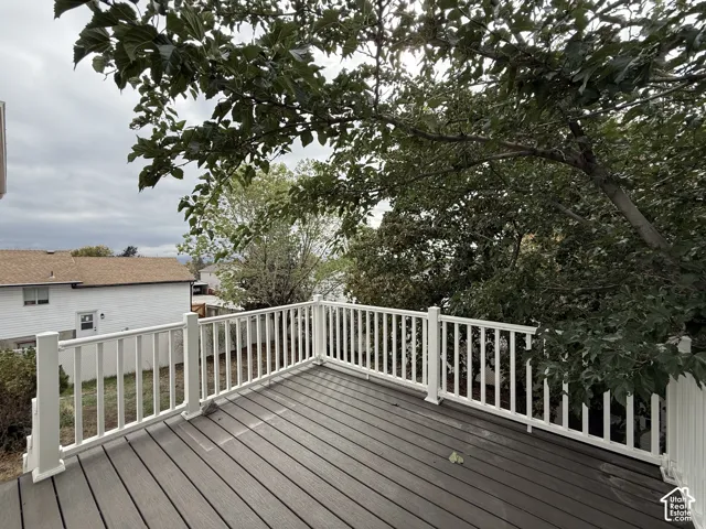 Elevated deck featuring composite decking, white vinyl railings, and mature tree canopy
