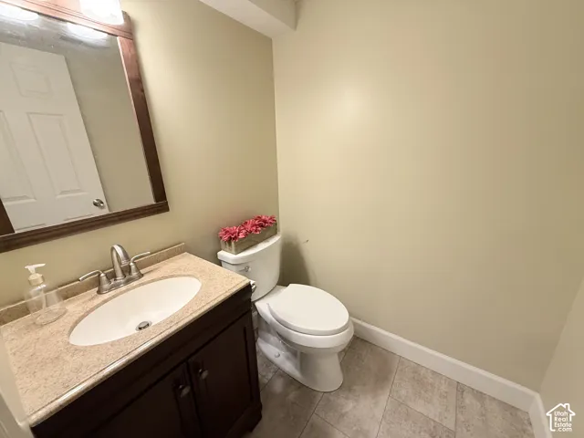 Dark wood-finish vanity with an integrated oval sink, stone-composite countertop, wall-mounted wood-framed mirror, and ceramic tile flooring