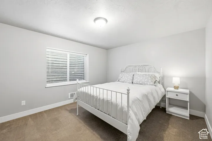 Neutral-toned interior space featuring light-colored wall paint, carpeted flooring, and a window with horizontal blinds
