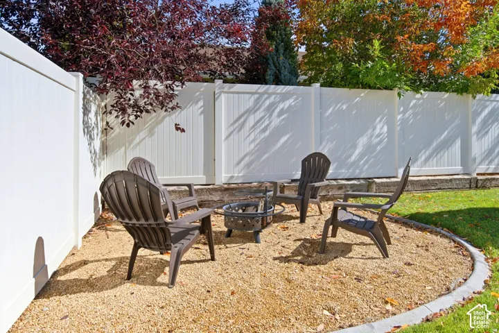 Backyard area featuring a white vinyl privacy fence, crushed stone ground cover, a curved concrete paver border, and a tiered stone retaining wall