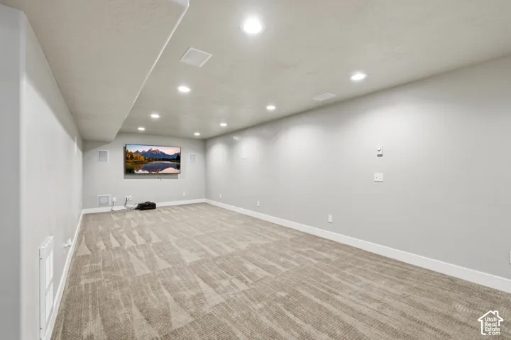 Neutral-toned carpeted flooring, recessed ceiling lighting, and integrated wall-mounted speakers