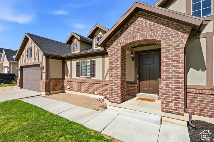 Tudor-inspired exterior featuring brick masonry, stucco-finish siding, timber-style trim, dormer windows, and a covered front entry