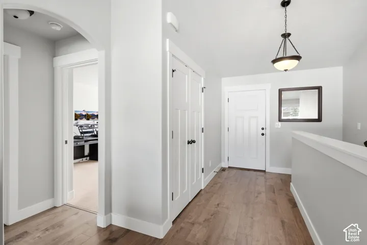 Entryway featuring wood-finish flooring, an arched architectural detail, white paneled interior doors, and a decorative pendant light fixture