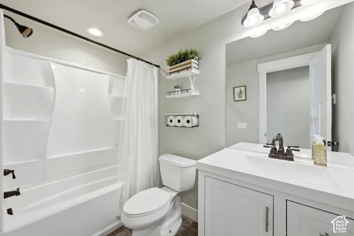 Bathroom featuring a vanity with a white integrated countertop, matte black faucet hardware, a shower-tub combination with a molded surround, and a wall-mounted light fixture
