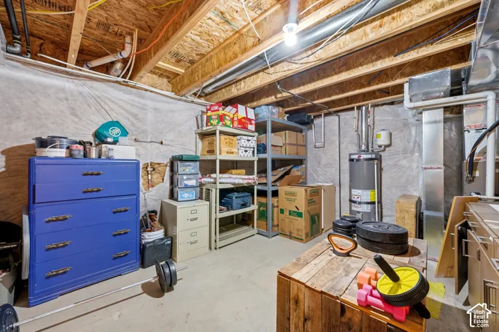Unfinished basement featuring concrete flooring, exposed wood ceiling joists, and a water heater