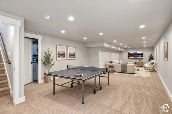 Expansive open-concept room featuring neutral wall-to-wall carpeting, recessed LED lighting, and integrated wall-mounted speakers