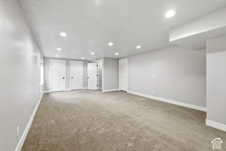 Neutral-toned interior space featuring recessed ceiling lighting, wall-to-wall carpeting, and multiple interior doors with matte black hardware