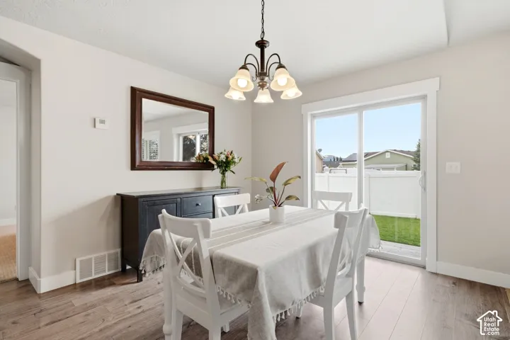 Dining area featuring wood-finish flooring, a multi-light chandelier, and a sliding glass door providing external access